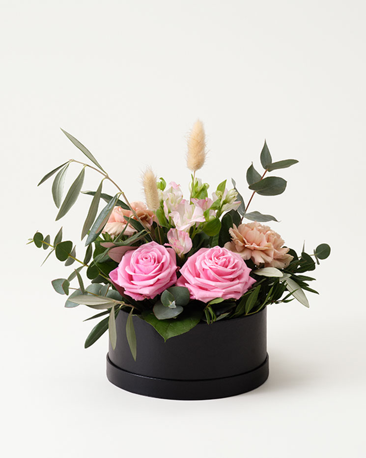 Fin blomsterdekoration i rund ask. Arrangemanget innehåller rosa rosor, alstroemeria, nejlikor, lagurus och gröna blad. Diameter på asken ca 18 cm. Finns att beställa som blommogram hos Interflora.