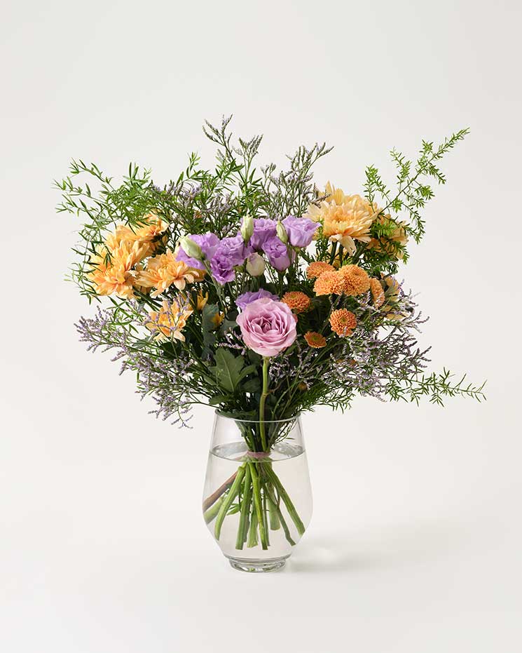 Superfin sommarbukett med blandade blommor i aprikosa och lila färgtoner plus vippigt dekorationsgrönt. Blommor: krysantemum, santini, limonium. Välj mellan fyra bukettstorlekar . De största innehåller också en lila ros (eller ett par stycken).
